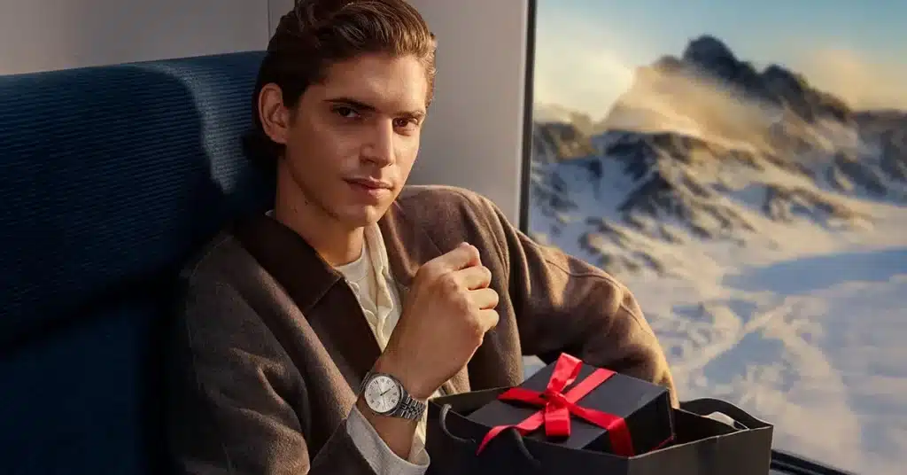 Tissot klokke på en manns arm. Menne sitter på et tog opg har en gave i fanget