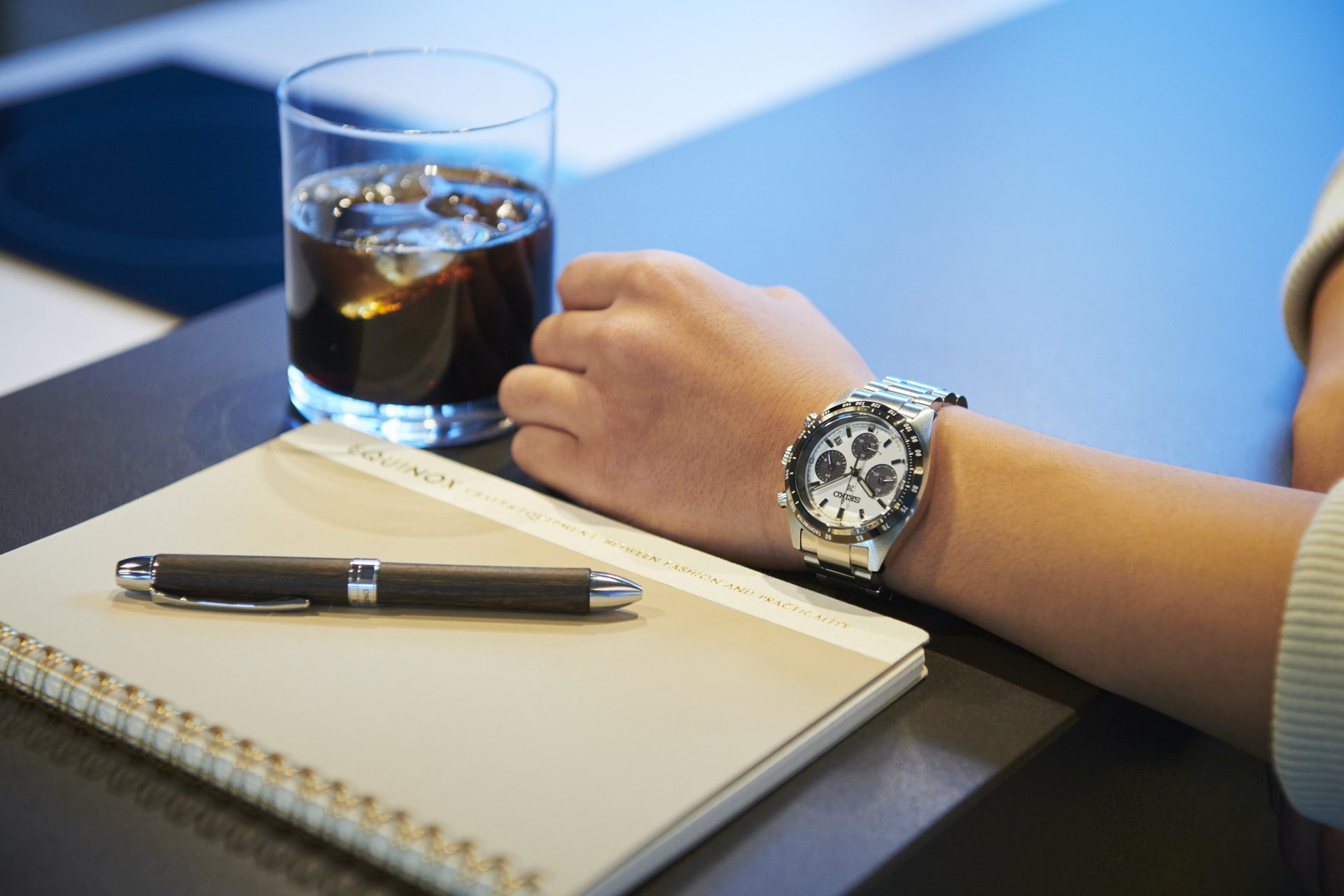 Seiko prospex på arm ved siden av glass og bok